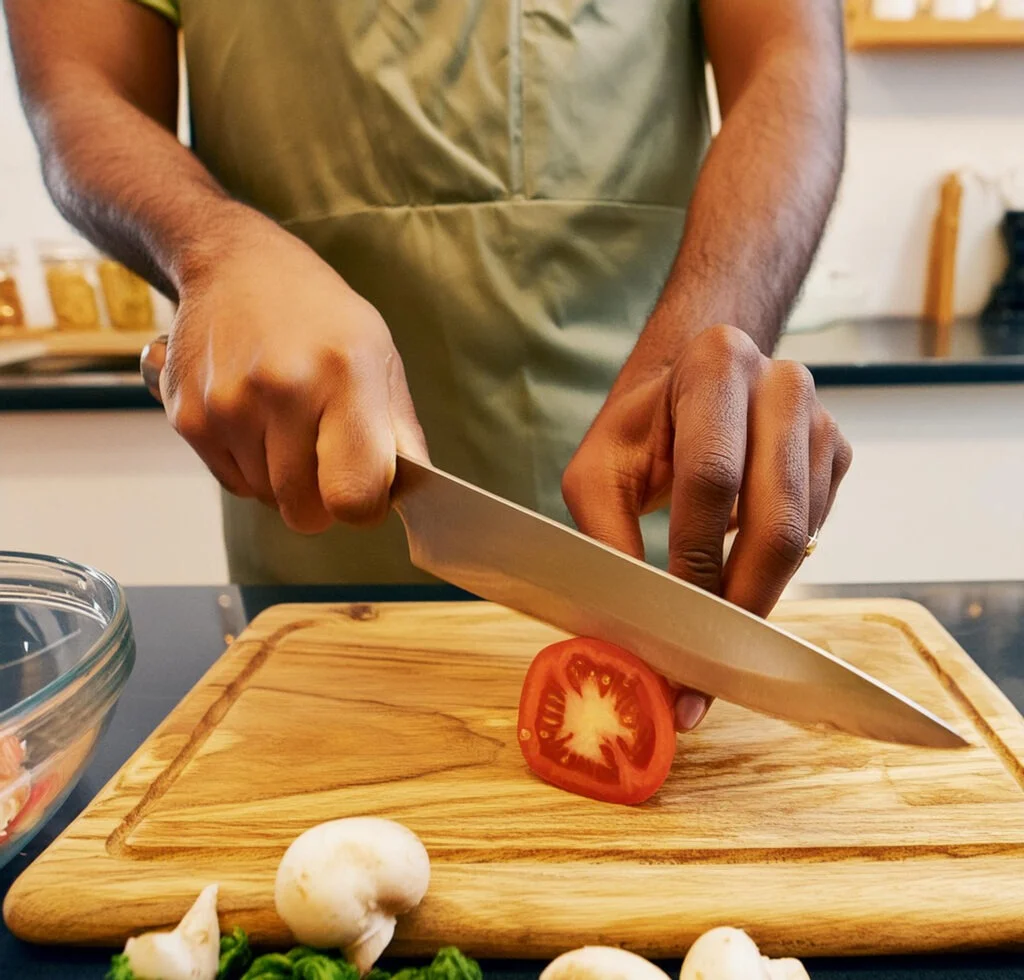 a person using a chef knife in a kitchen - bladesjournal